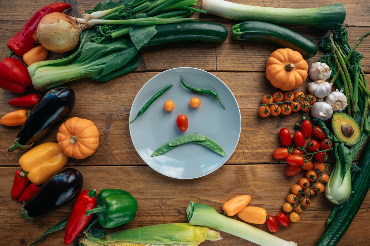 Vegetales, hortalizas y frutas dibujan una cara triste en un plato Vegetales, hortalizas y frutas dibujan una cara triste en un plato