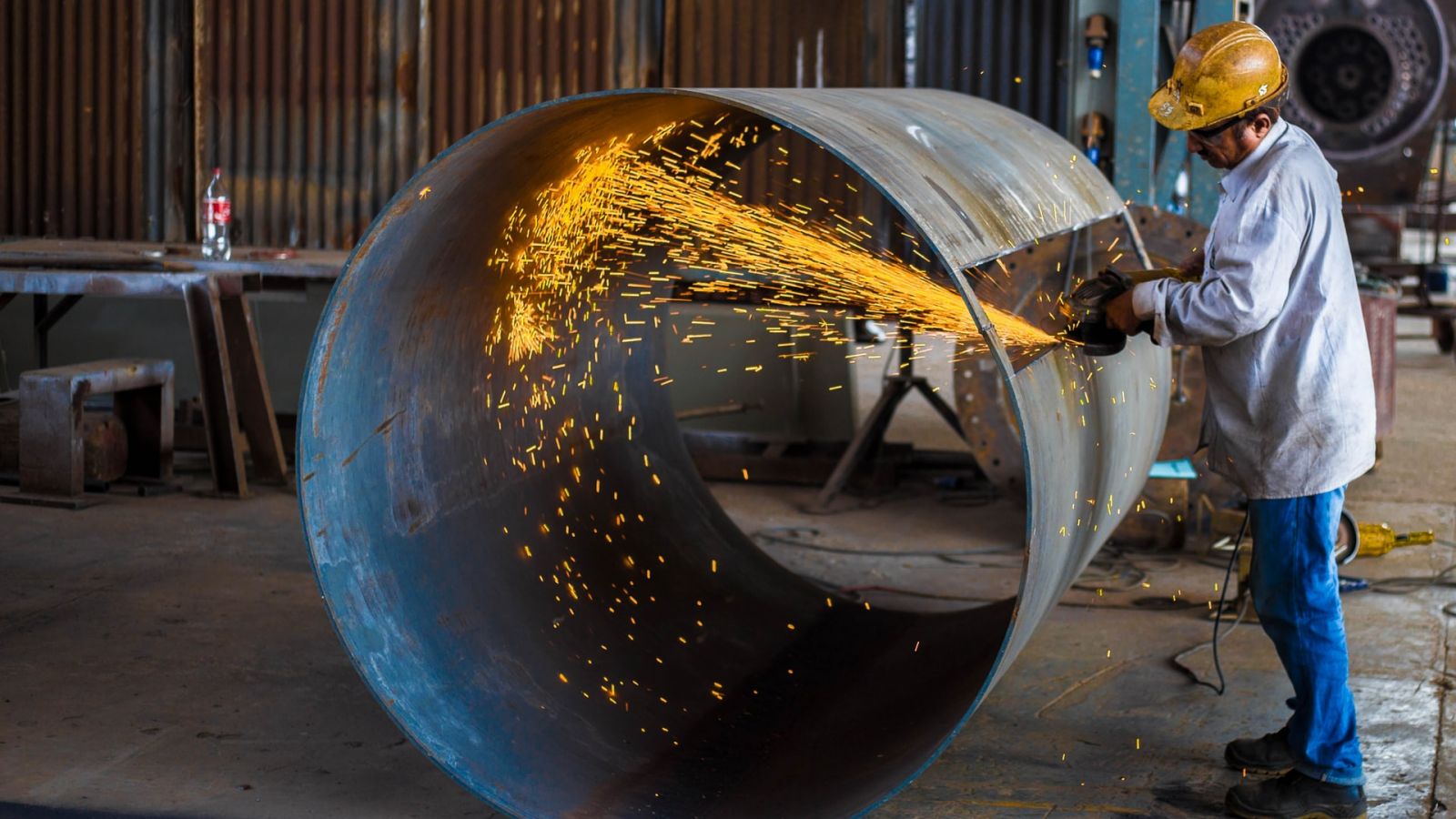 Obrero cortando un tubo de metal con la protección adecuada en industria Obrero cortando un tubo de metal con la protección adecuada en industria