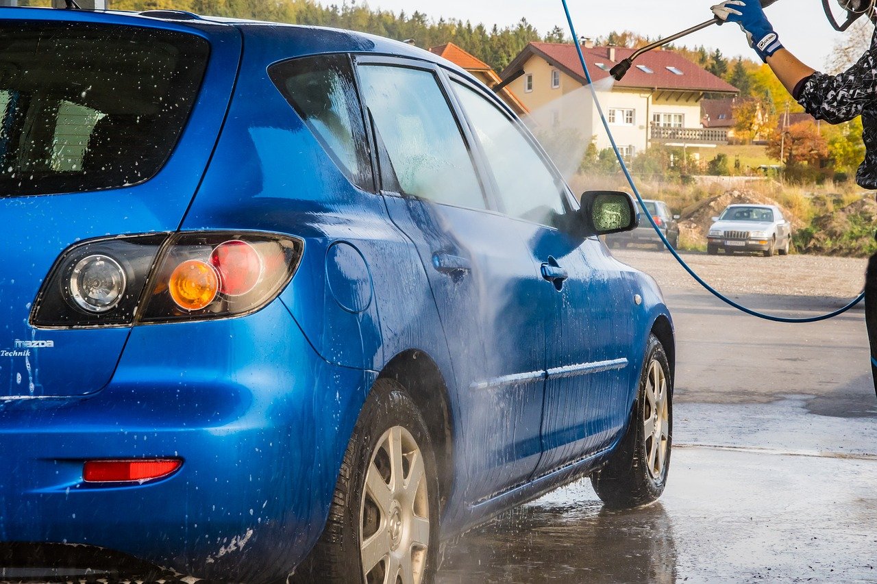 Coche azul es limpiado con una hidrolimpiadora a presión