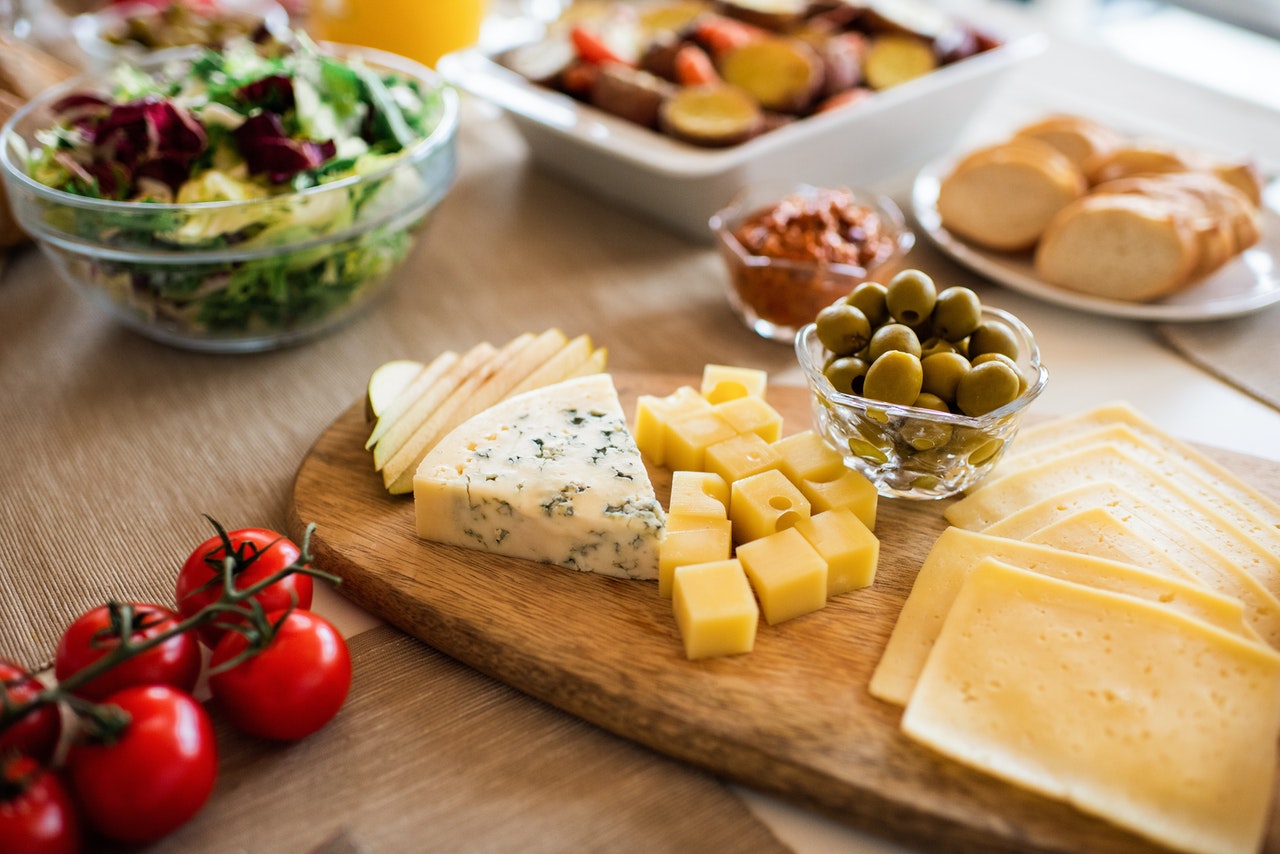 Quesos, tomates y tapas situadas en una mesa marrón Quesos, tomates y tapas situadas en una mesa marrón