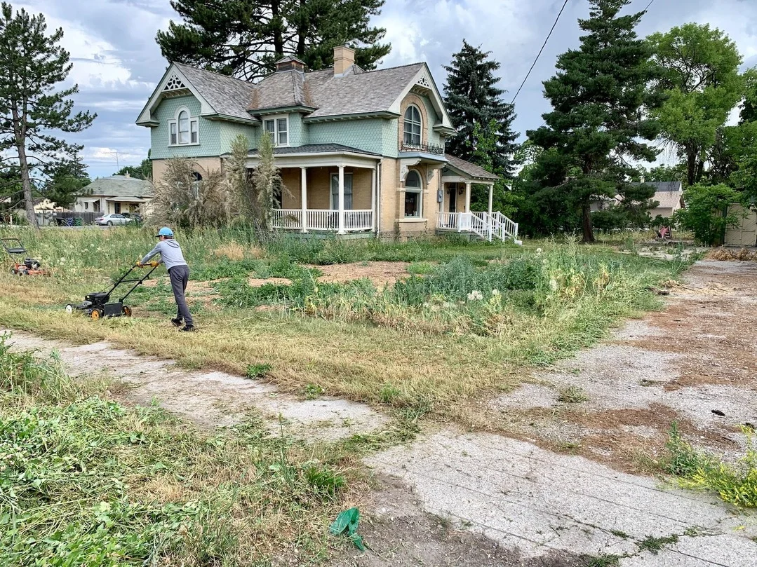 A man outside mowing the lawn in front of a blue house