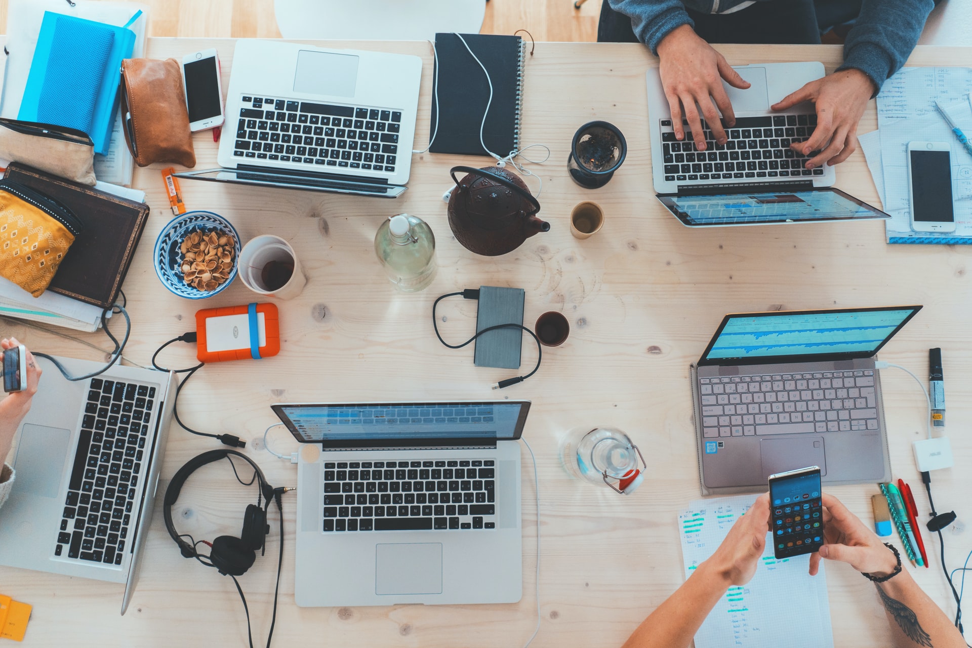 Messy desk from above with people working on computers together