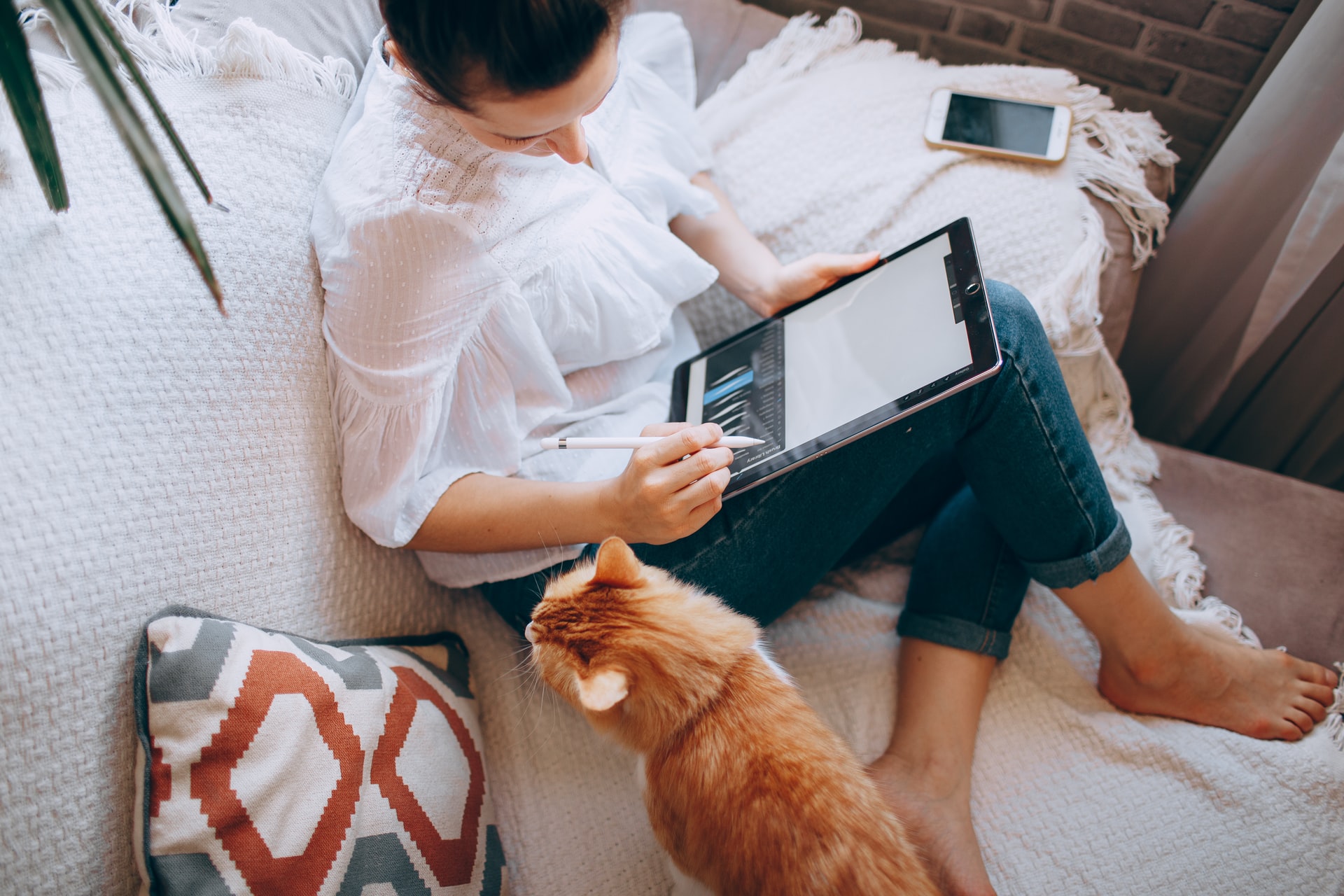 Frau, die eine Checkliste für das Home Office benutzt, während sie auf der Couch arbeitet